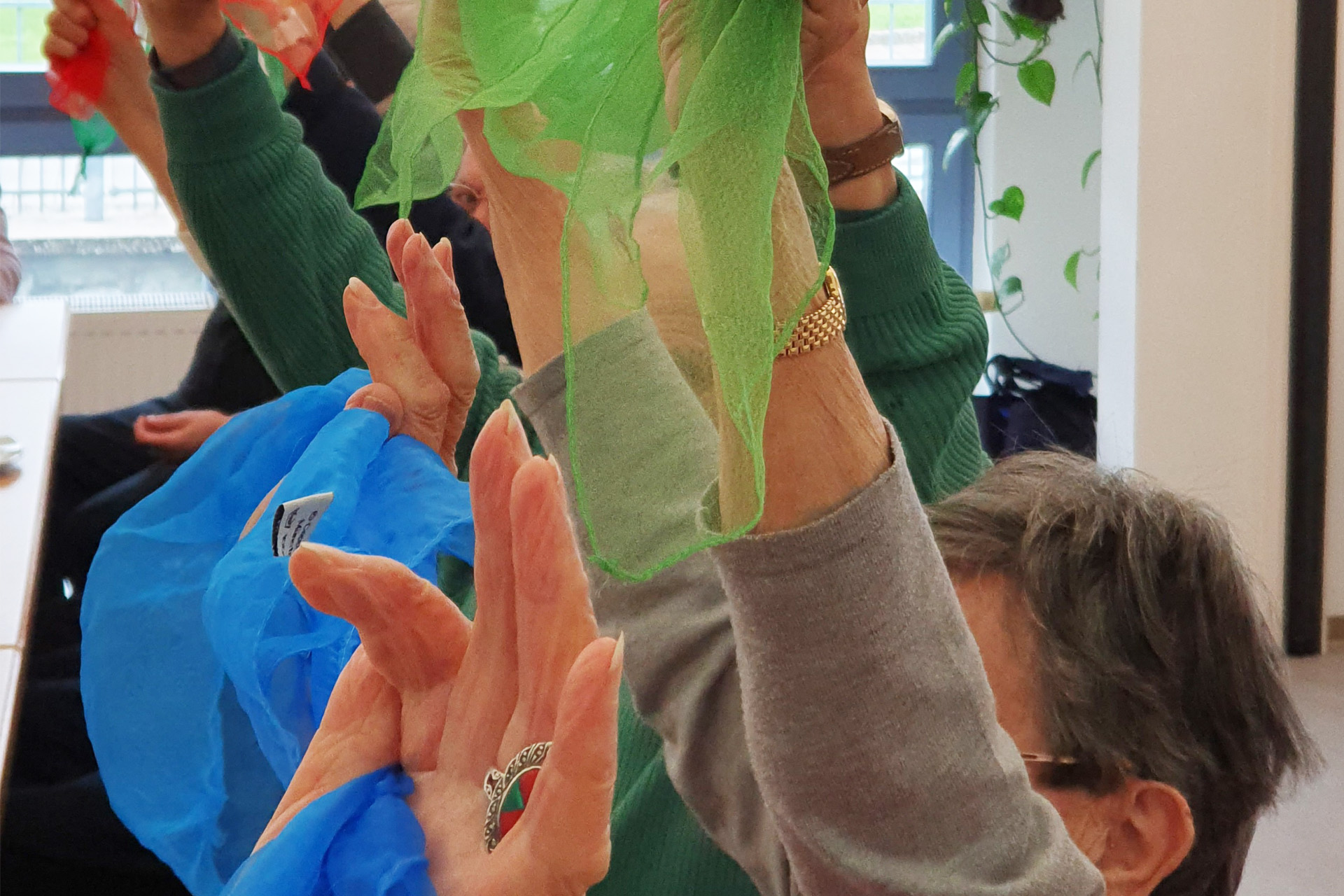 Mehrere Menschen halten ihre Arme nach oben. In den Haenden halten Sie Stofftuecher