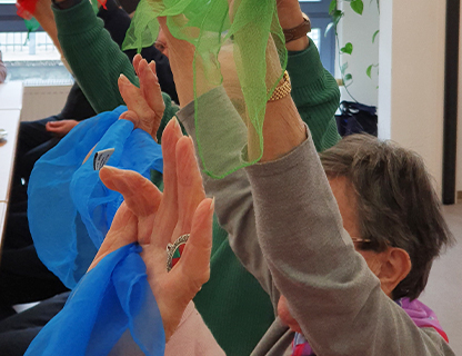 Mehrere Menschen halten ihre Arme nach oben. In den Haenden halten Sie Stofftuecher