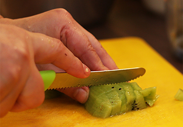 ein Mensch schneidet eine Kiwi auf einem Schneidebrett